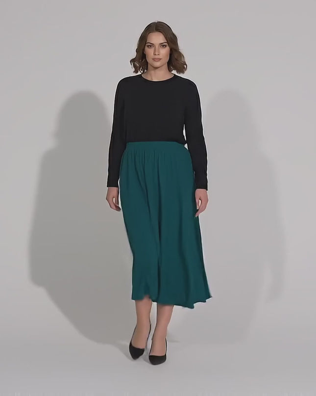 Видео в студийна среда с неутрален фон, показващо как модел носи Официална разкроена пола големи размери в масленозелено, докато върви бавно към камерата