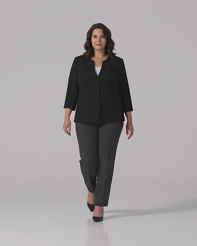 Видео в студийна среда с неутрален фон, на което плюс сайз манекенка върви бавно към камерата, облечена в Елегантно черно сако големи размери с акцент роза