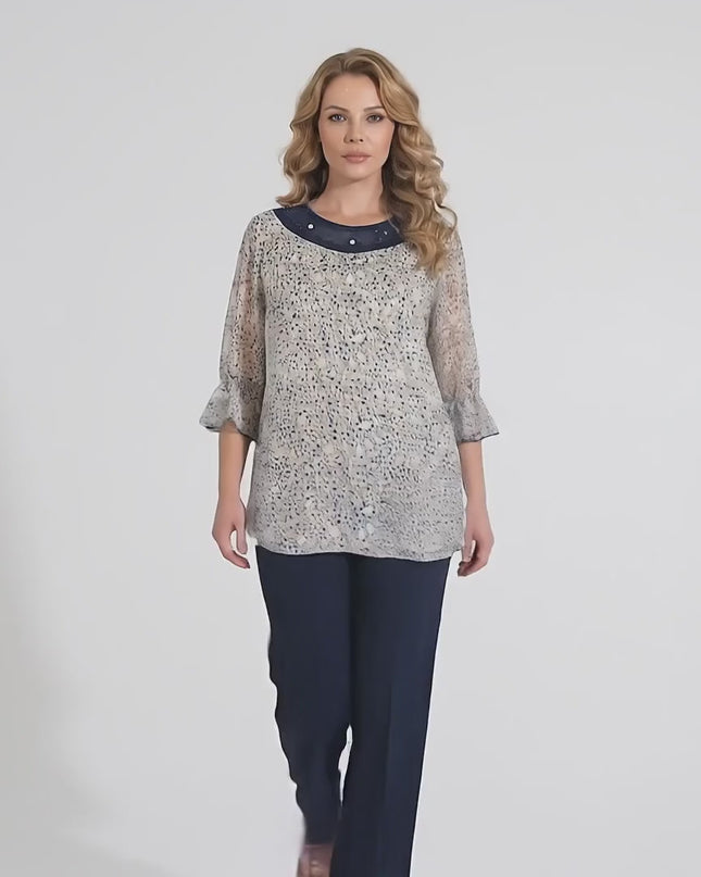 Видео в студийна среда, на което макси модел се разхожда бавно към камерата на неутрален фон, носейки Официална бяла макси туника на цветя с перли и тюл