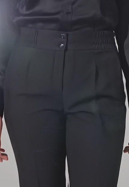 Видео в студийна среда на неутрален фон, в което модел върви бавно към камерата и носи Официален дамски черен панталон с прав крачол и ластик на талията големи размери