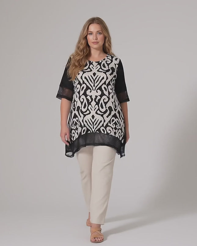 Студийно видео на неутрален фон, в което плюс сайз модел върви бавно към камерата, облечена в Черна лятна туника големи размери с мрежести елементи