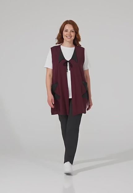 Видео на модел, който върви към камерата и представя Разкроен макси елек в цвят бордо с елементи от еко кожа в студио