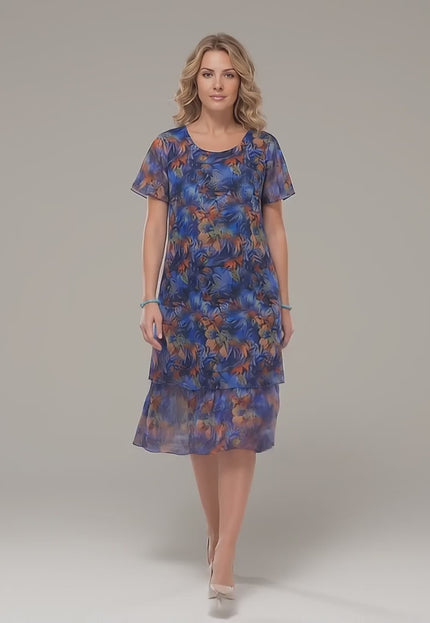 Видео в студийна среда, показващо макси модел, който върви бавно към камерата и носи Официална макси рокля от пъстър шифон с разкроен силует