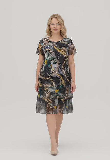 Видео в студийна среда, на което макси модел върви бавно към камерата, носейки Официална разкроена макси рокля от шифон в шарен десен