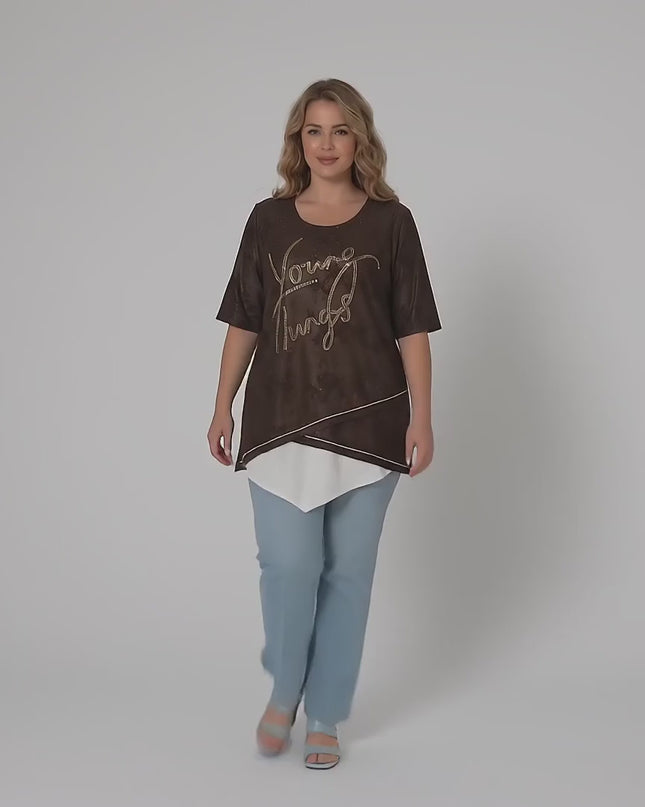 Видео в студио с неутрален фон, в което макси модел е облечен с Официална макси туника в кафяво с асиметрична кройка и върви бавно към камерата