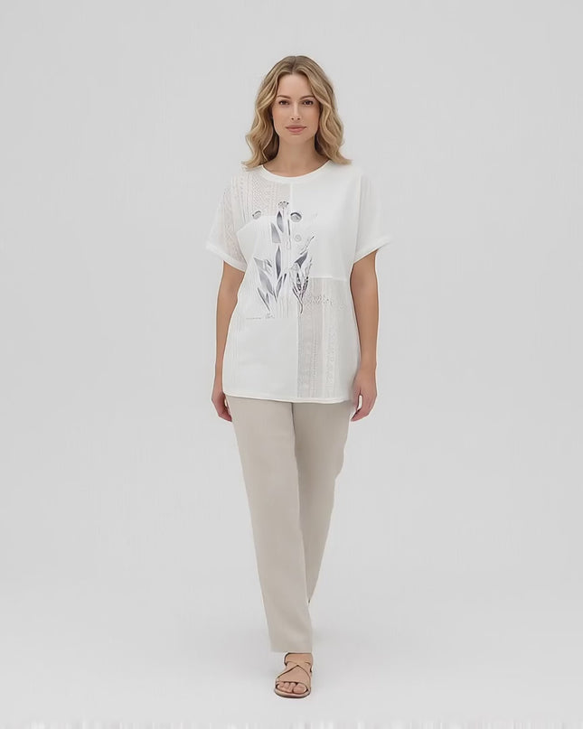 Макси модел носи Бяла лятна туника големи размери с флорална апликация, докато върви бавно към камерата в студио с неутрален фон