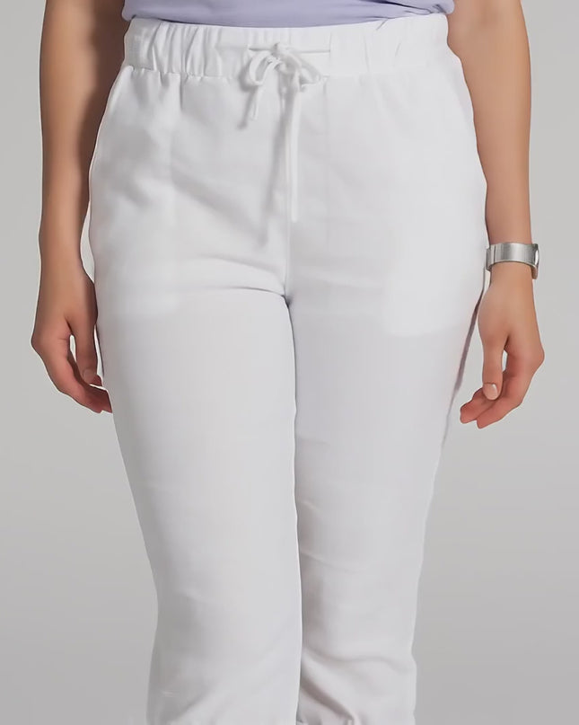 Продуктово видео в студийна среда, показващо плюс сайз модел на неутрален фон, който върви бавно към камерата и носи Бял дамски панталон под коляното с връзки и джобове