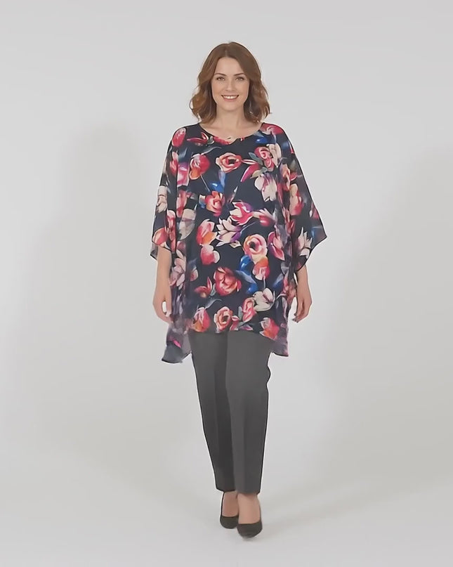 Видео в студио с неутрален фон, на което макси модел върви бавно към камерата, носейки Тъмносиня официална макси туника на цветя тип пончо