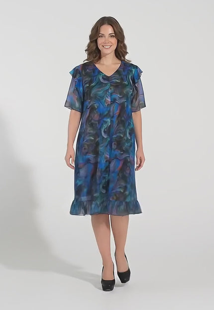 Студийно видео с неутрален фон, на което плюс сайз модел върви бавно към камерата, носейки Шарена официална рокля големи размери с ефектен ръкав и шифон