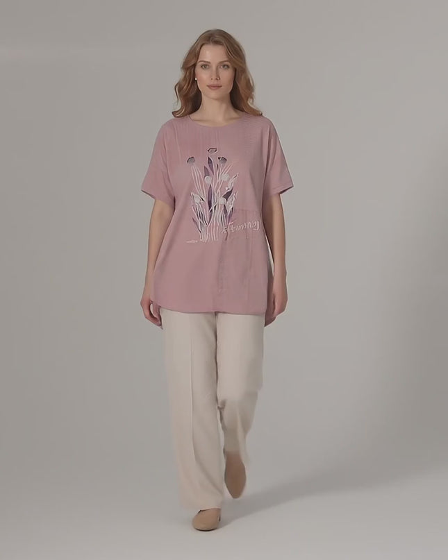 Продуктово видео в студио, показващо Розова лятна макси туника с дантела и флорални мотиви, носена от макси модел, който върви бавно към камерата на неутрален фон