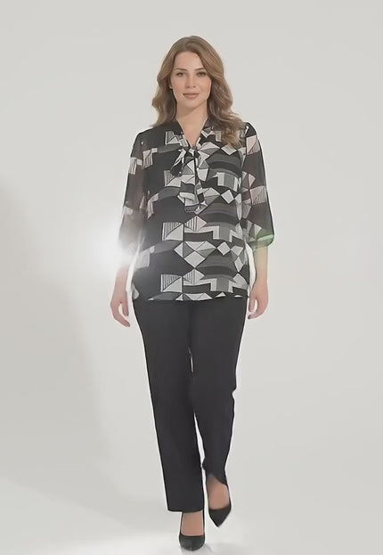 Продуктово видео заснето в студио което показва макси модел да върви бавно към камерата носейки Официална черна макси туника с панделка и 7/8 ръкав