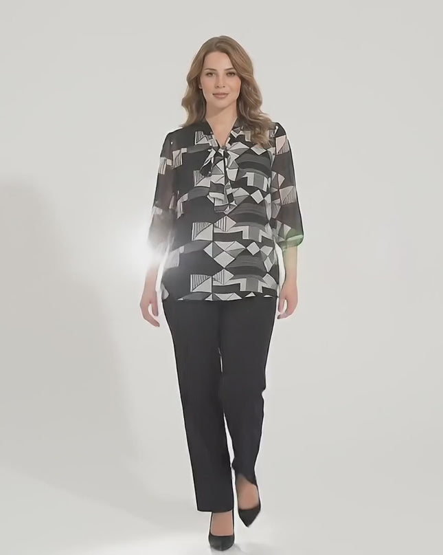 Продуктово видео заснето в студио което показва макси модел да върви бавно към камерата носейки Официална черна макси туника с панделка и 7/8 ръкав