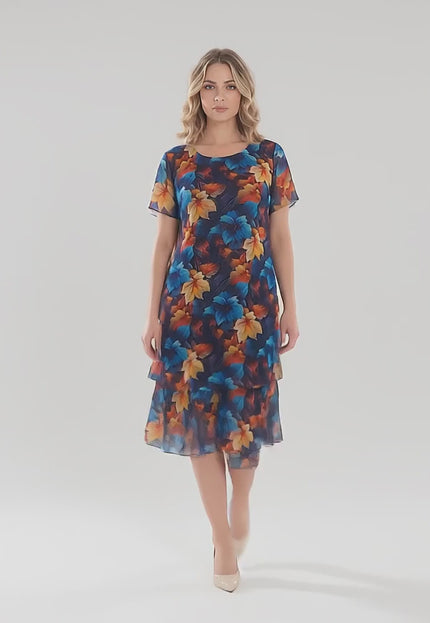 Продуктово видео в студио с неутрален фон, показващо плюс сайз модел, който върви бавно към камерата, носейки Официална тъмносиня макси рокля от шифон с многоцветен принт на листа