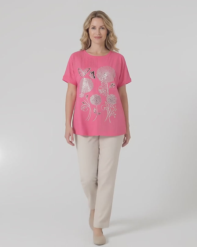 Жена плюс размер модел носи Лятна памучна туника в цвят корал с красива апликация на цветя, докато върви бавно към камерата в студийна среда на неутрален фон