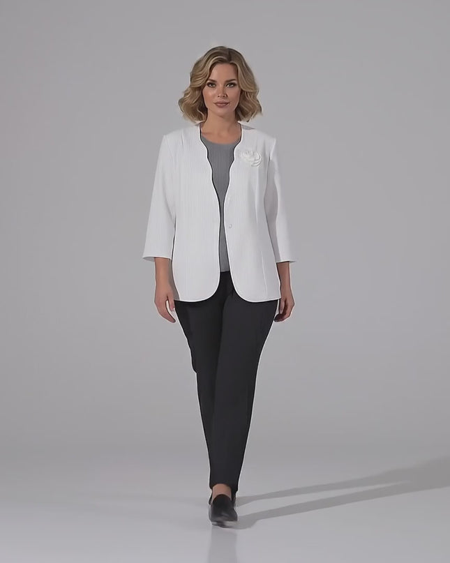 Видео в студийна среда на неутрален фон, показващо плюс сайз модел, който върви бавно към камерата и носи Официално дамско бяло сако големи размери с брошка роза