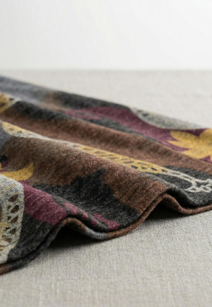 Детайл отблизо на меката материя на разкроена ежедневна рокля, показващ текстурата на вискозното трико и богатия принт с пейсли мотиви в кафявата гама.