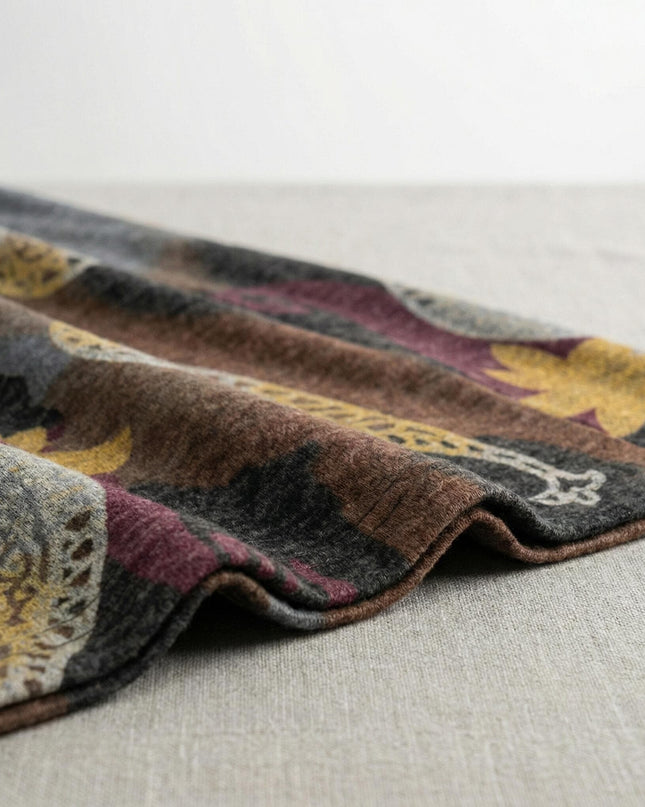 Детайл отблизо на меката материя на разкроена ежедневна рокля, показващ текстурата на вискозното трико и богатия принт с пейсли мотиви в кафявата гама.