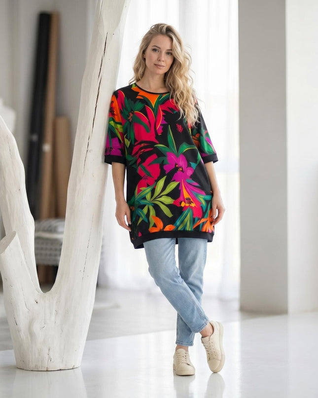 Шарена лятна туника с къс ръкав и тропически флорален принт на черен фон, представена в цял ръст върху модел.