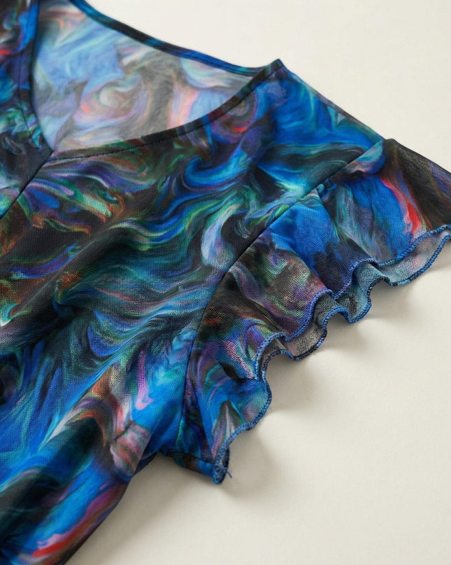 Детайл отблизо на ефектен ръкав от шифон на шарена официална рокля големи размери, показващ абстрактния принт в синьо и вълнообразния подгъв.