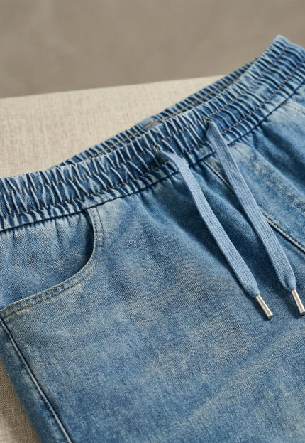 Детайл отблизо на сини макси дамски дънки, показващ еластичната талия с регулируеми връзки и горната част на страничните джобове.