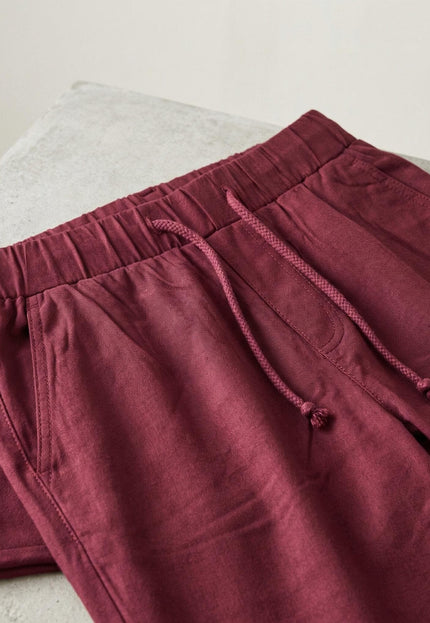 Детайлен кадър на талията на спортно-елегантен макси панталон в цвят бордо, показващ еластичния колан с връзки и страничните джобове.