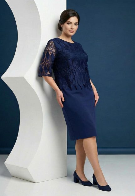 Тъмносиня официална макси рокля с дантела и права кройка, представена в цял ръст до бял декоративен елемент.