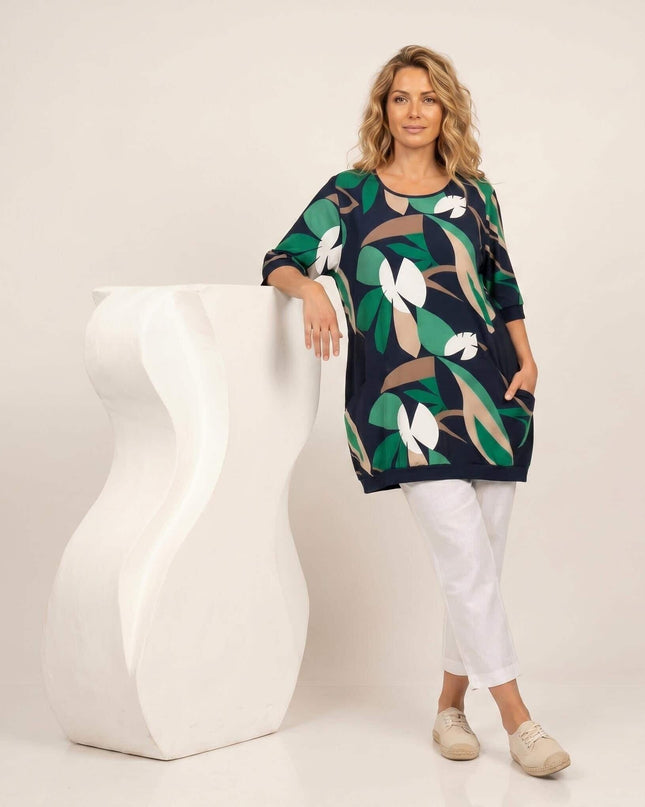 Тъмносиня лятна туника големи размери с флорален принт. Модел в цял ръст, демонстриращ разкроената кройка, обло деколте и предни джобчета, на бял фон.